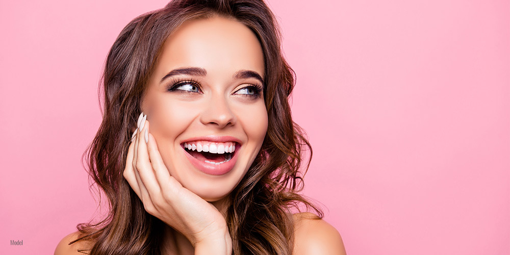 Female smiling behind pink backdrop. 