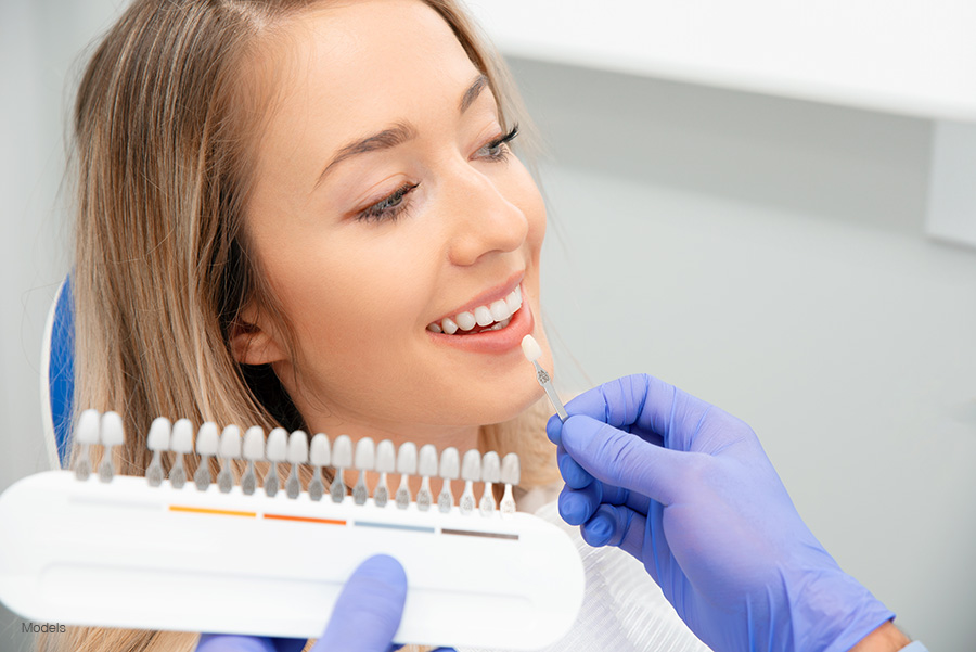 A woman has her shade of dental restoration matched with her natural teeth.